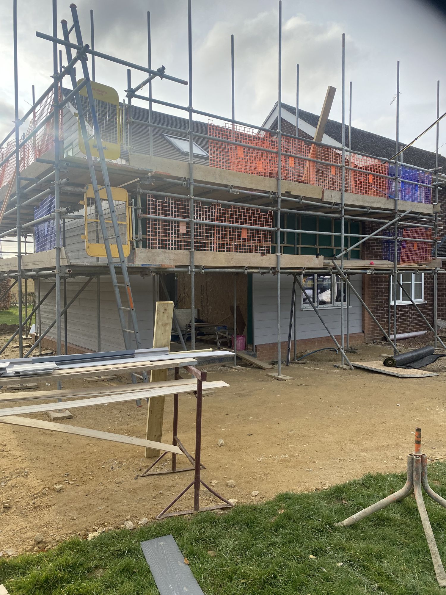 Two-storey extension under construction, wrapped in scaffolding