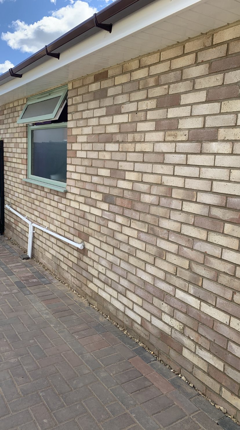 Finished buff brick wall with new window, fascia and paving